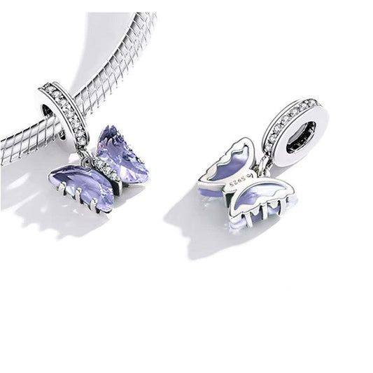 A Sterling 925 silver charm featuring a purple butterfly with clear crystal embellishments on the wings, attached to a loop with cubic zirconia. in a pandora bracelet