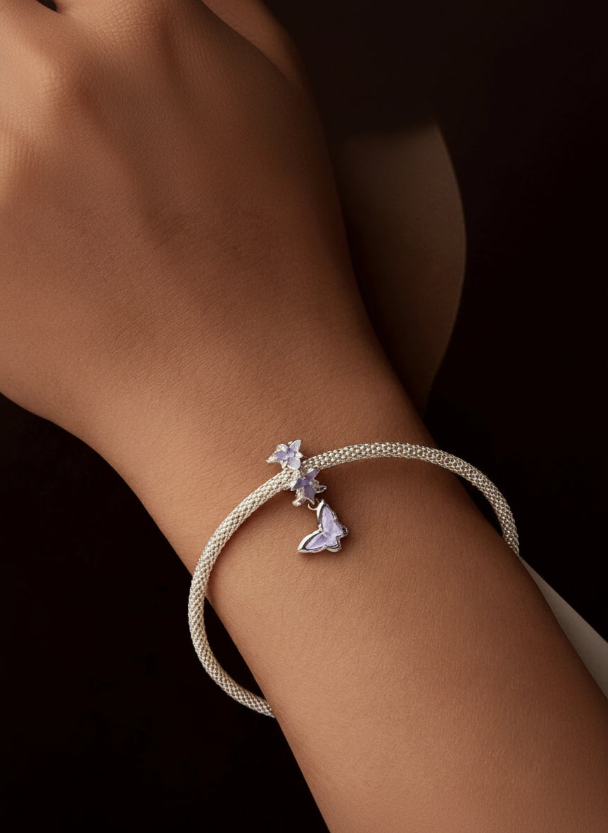 Bracelet with butterfly charm on a wrist against a dark background