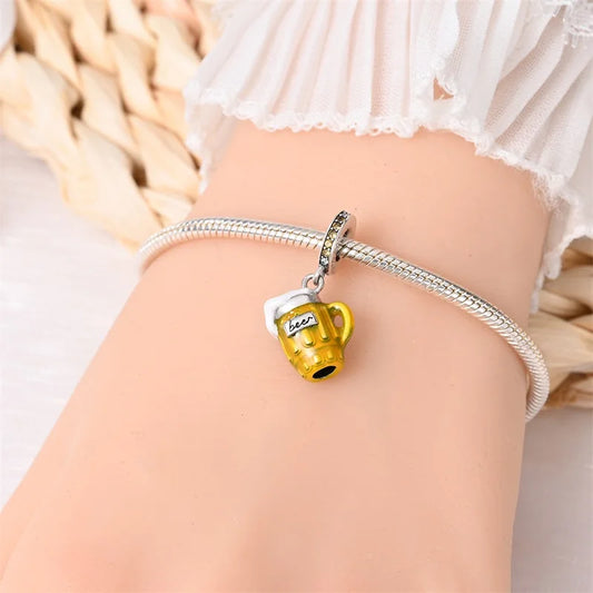 Silver bracelet with a yellow beer mug charm on a person's wrist.