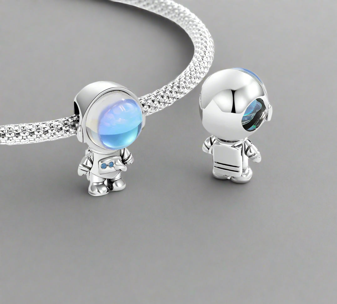 sterling 925 silver astronaut-themed charms with blue gemstones on a white background