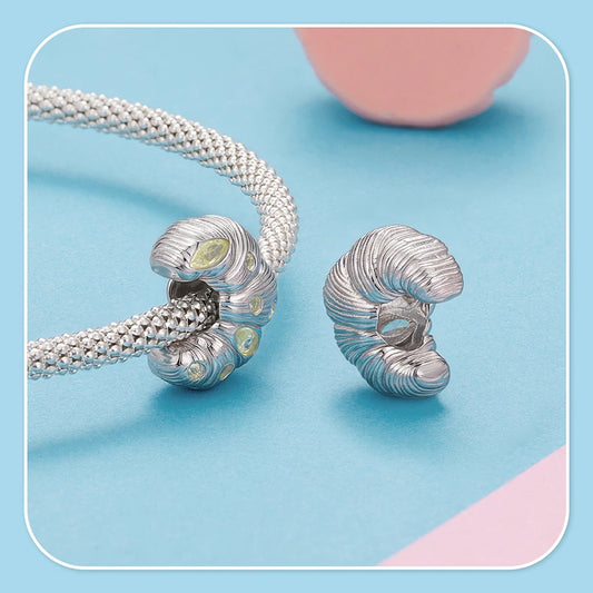 Silver charm with a textured design on a light blue background in a form of croissant that compatible pandora bracelet