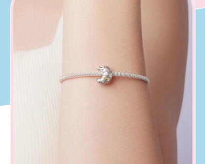Silver bracelet with a croissant charm worn on a wrist against a light blue background
